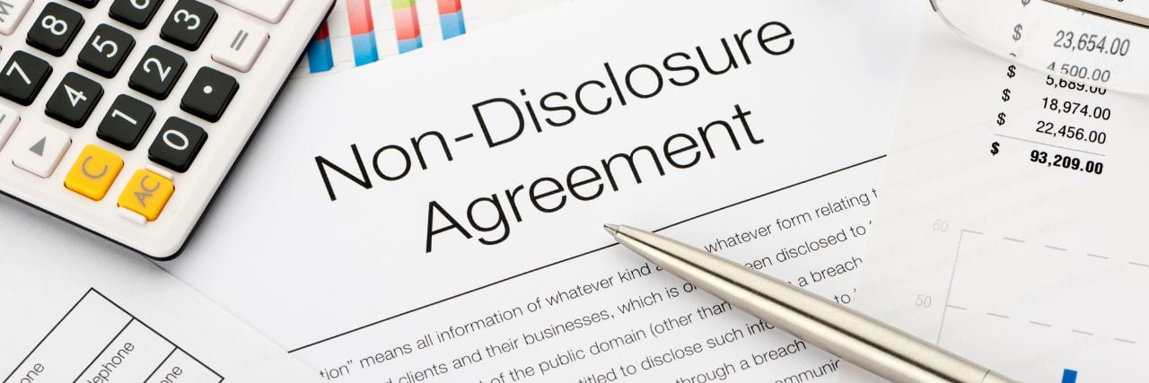 a non disclosure agreement on a table with a pen and a calculator