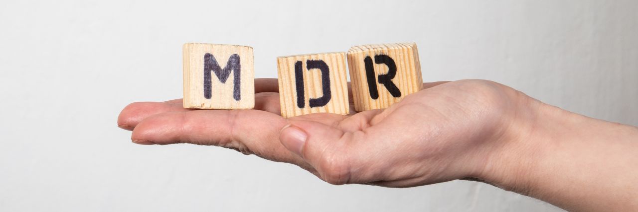 a person holding blocks with the letters MDR written on it