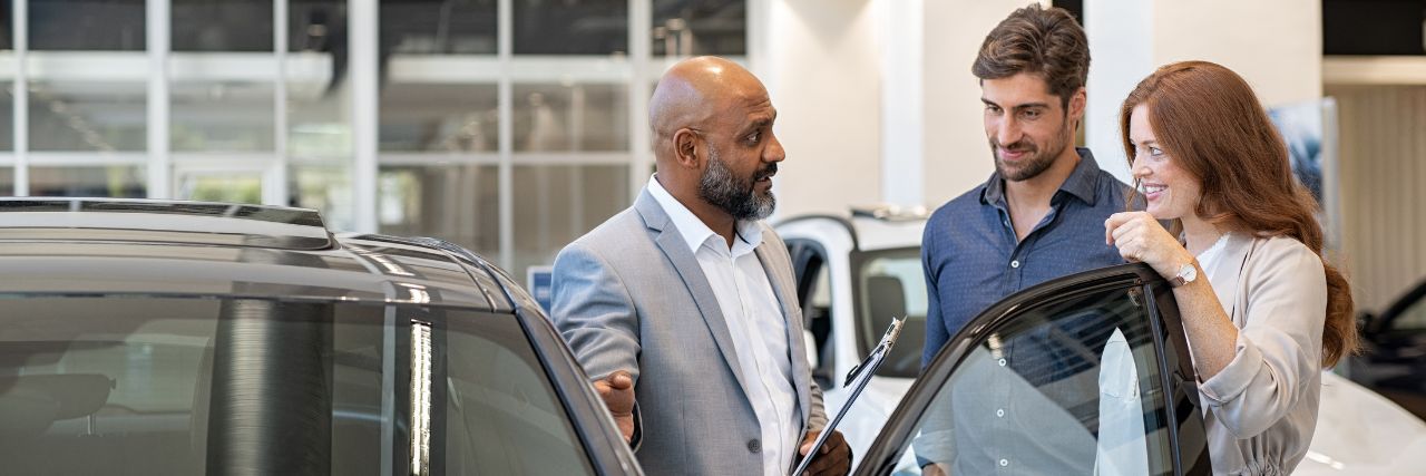 a salesperson selling a car to a couple in an auto dealership