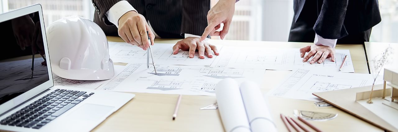 a couple of architects discussing a building plan on top of  a table