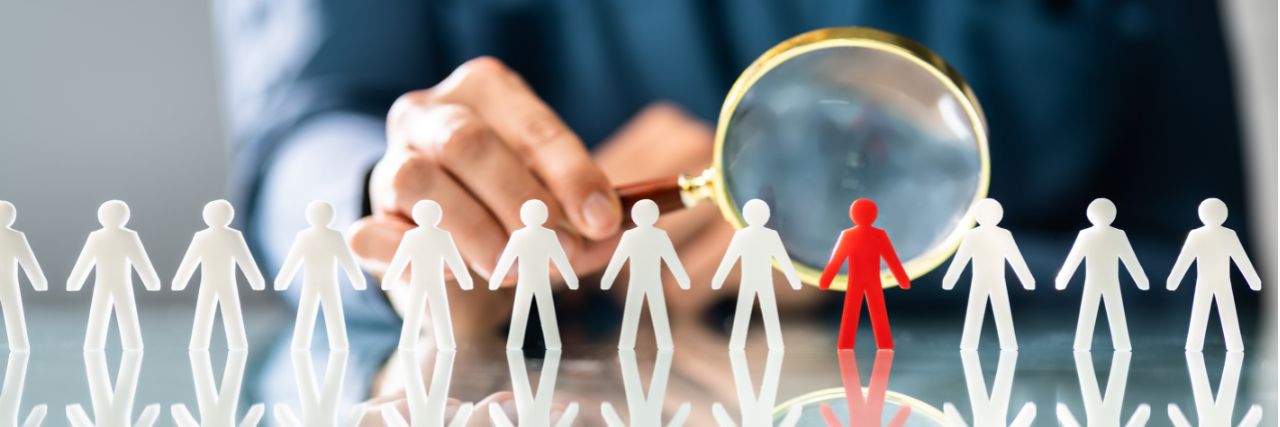 a person holding a magnifying glass over interested possible IT staff