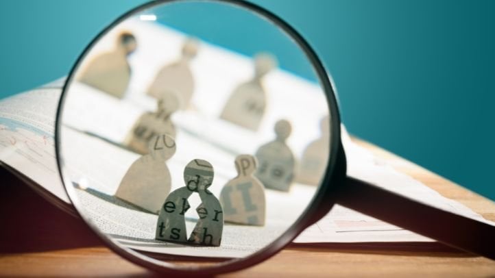 a magnifying glass over paper cutout shaped like people