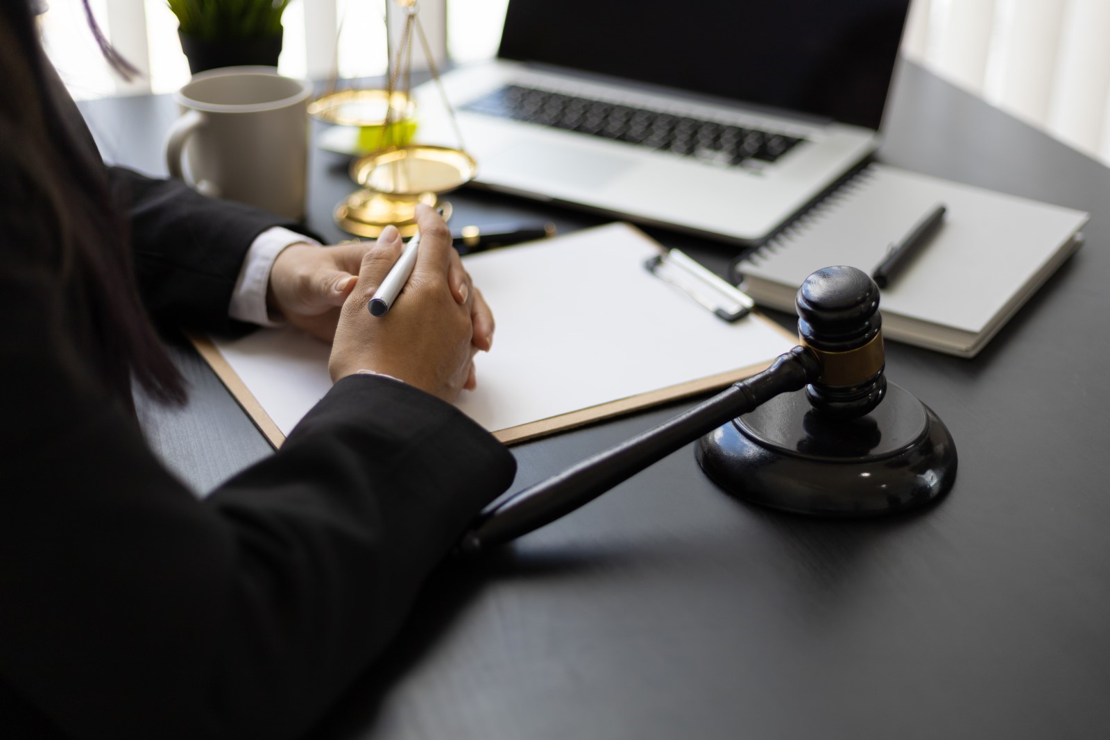 a lawyer seated with his hands on their desk with a gavel and laptop